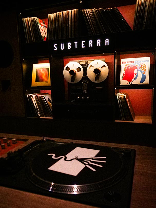 SonoLux logo on slip mat with vinyl collection and reel to reel in the background