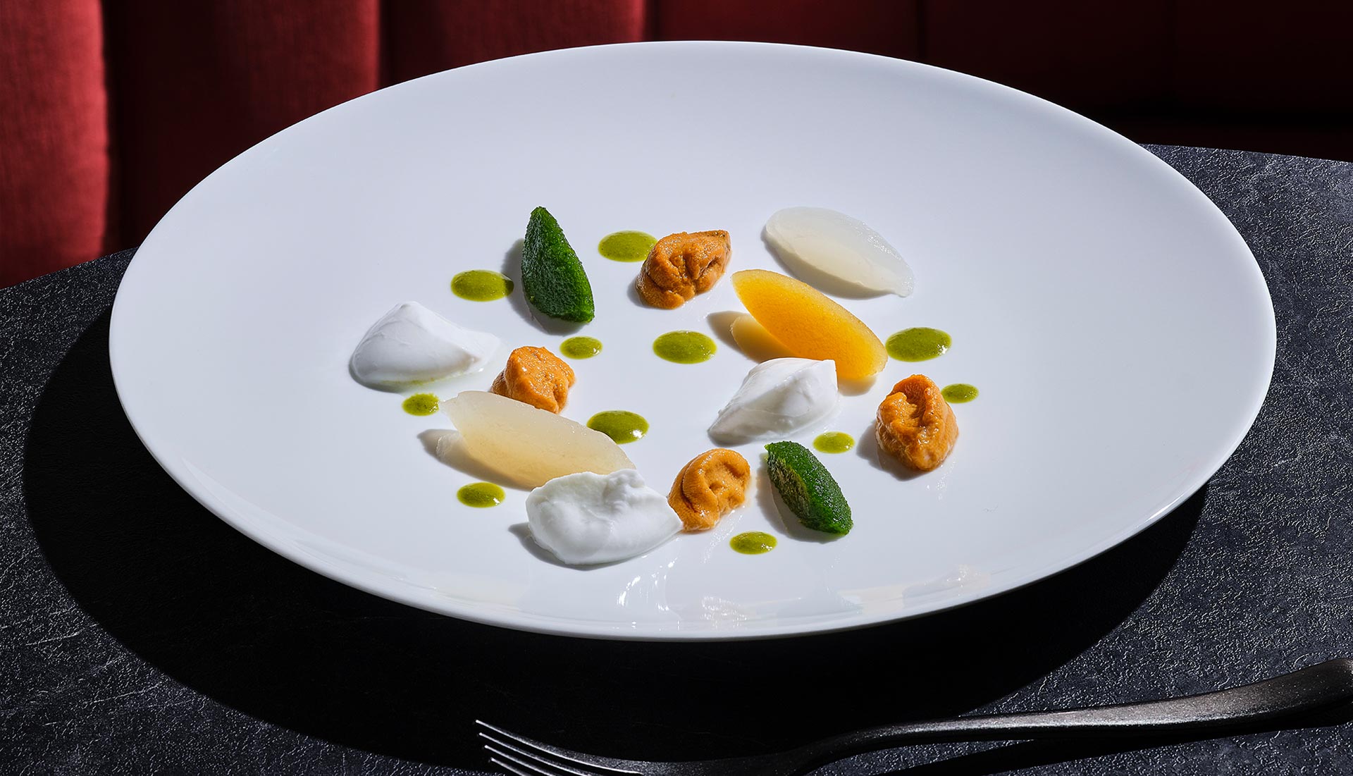 Sea urchin beautifully plated with red banquette in background